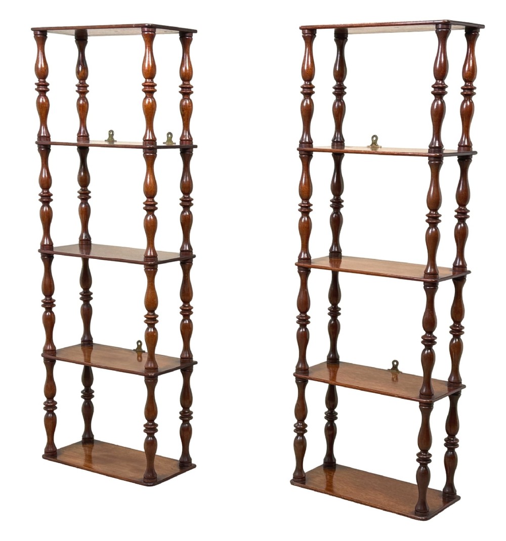 A pair of tall mid-19th-century mahogany wall-hanging shelves featuring five open tiers supported by turned spindles.