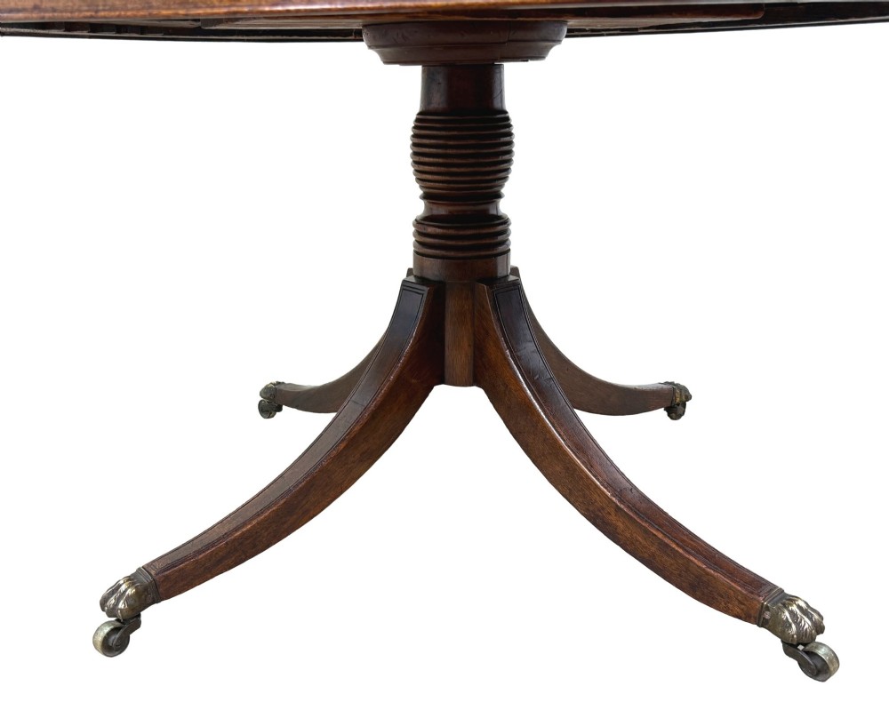 A circular Georgian mahogany drum table featuring a brown leather top, frieze drawers with brass ring handles, and a pedestal base with four splayed legs on brass paw castors. View VI