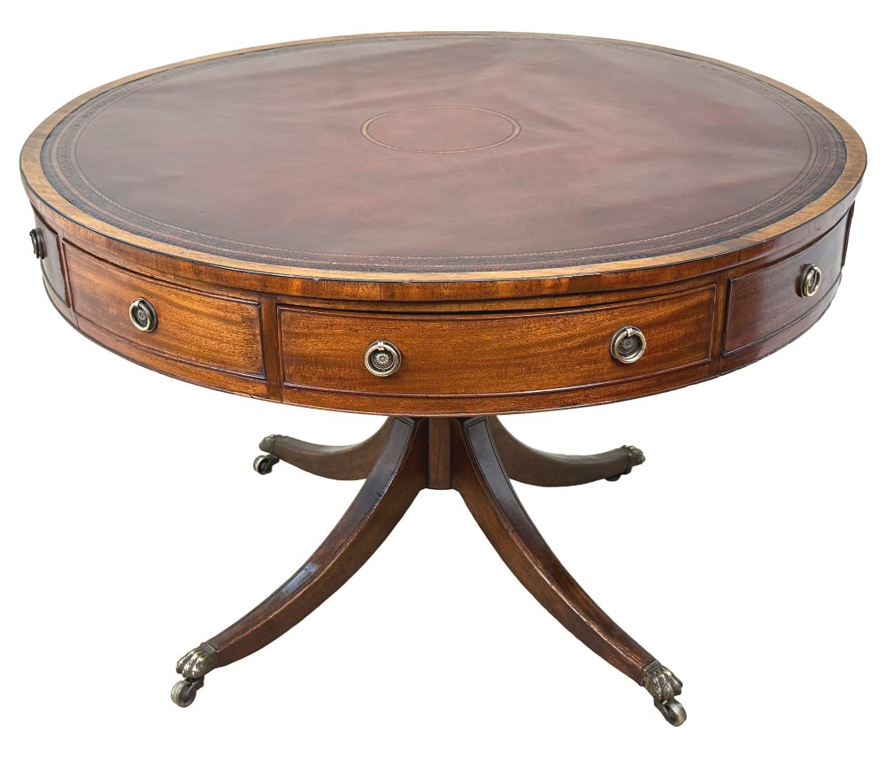 A circular Georgian mahogany drum table featuring a brown leather top, frieze drawers with brass ring handles, and a pedestal base with four splayed legs on brass paw castors. View VII