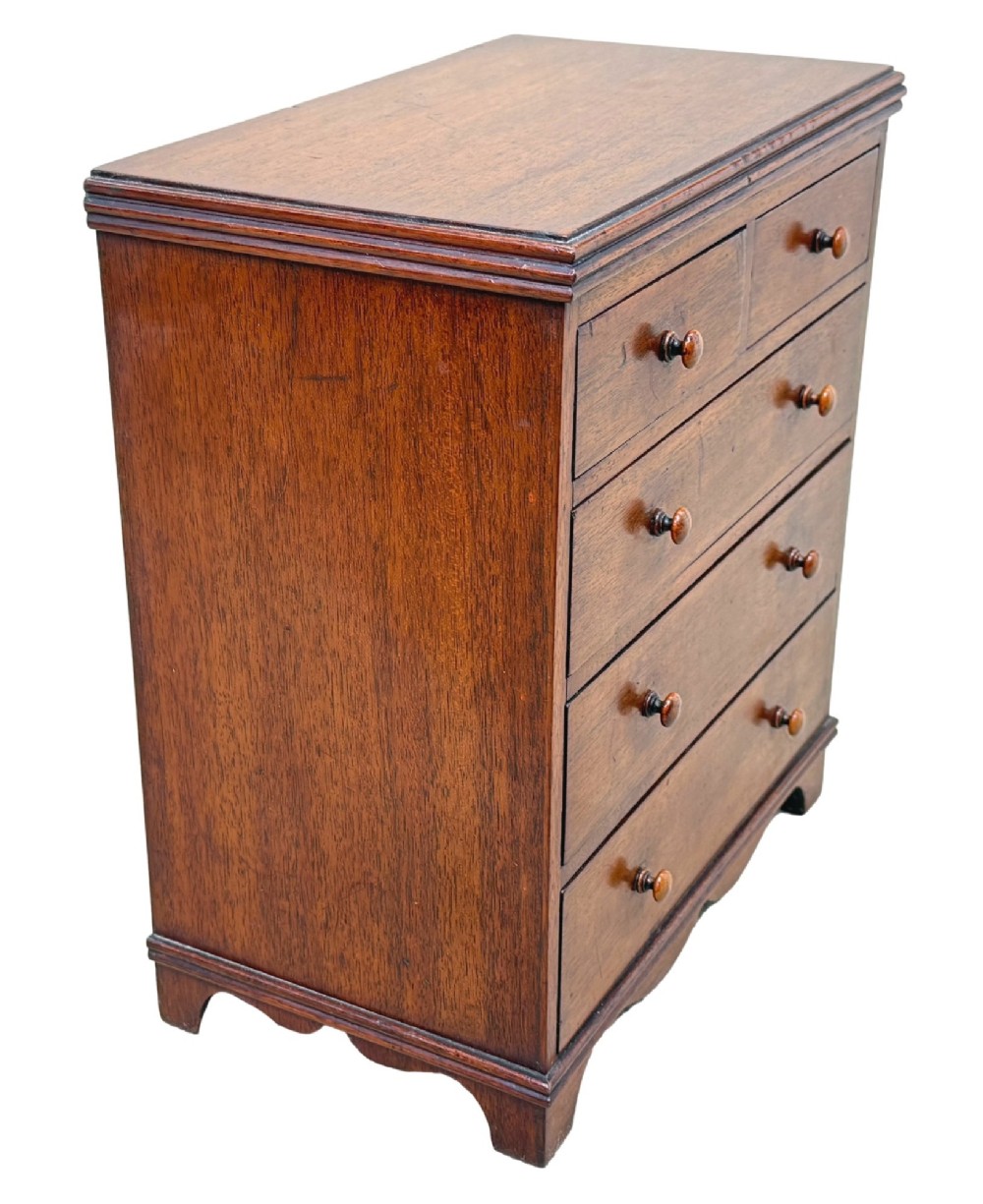 A miniature early nineteenth-century mahogany chest of drawers with two short over three long graduated drawers, turned wooden knobs, and a shaped apron base. View III
