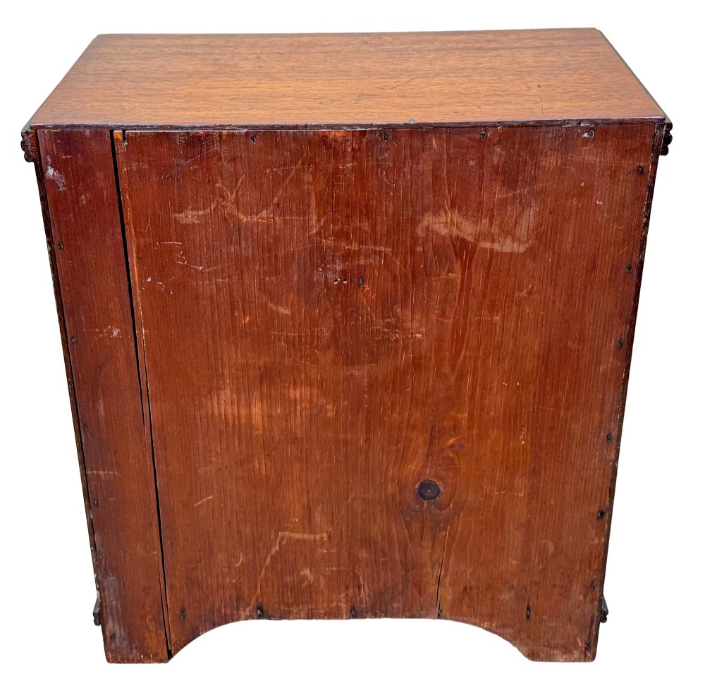 A miniature early nineteenth-century mahogany chest of drawers with two short over three long graduated drawers, turned wooden knobs, and a shaped apron base. View VIII