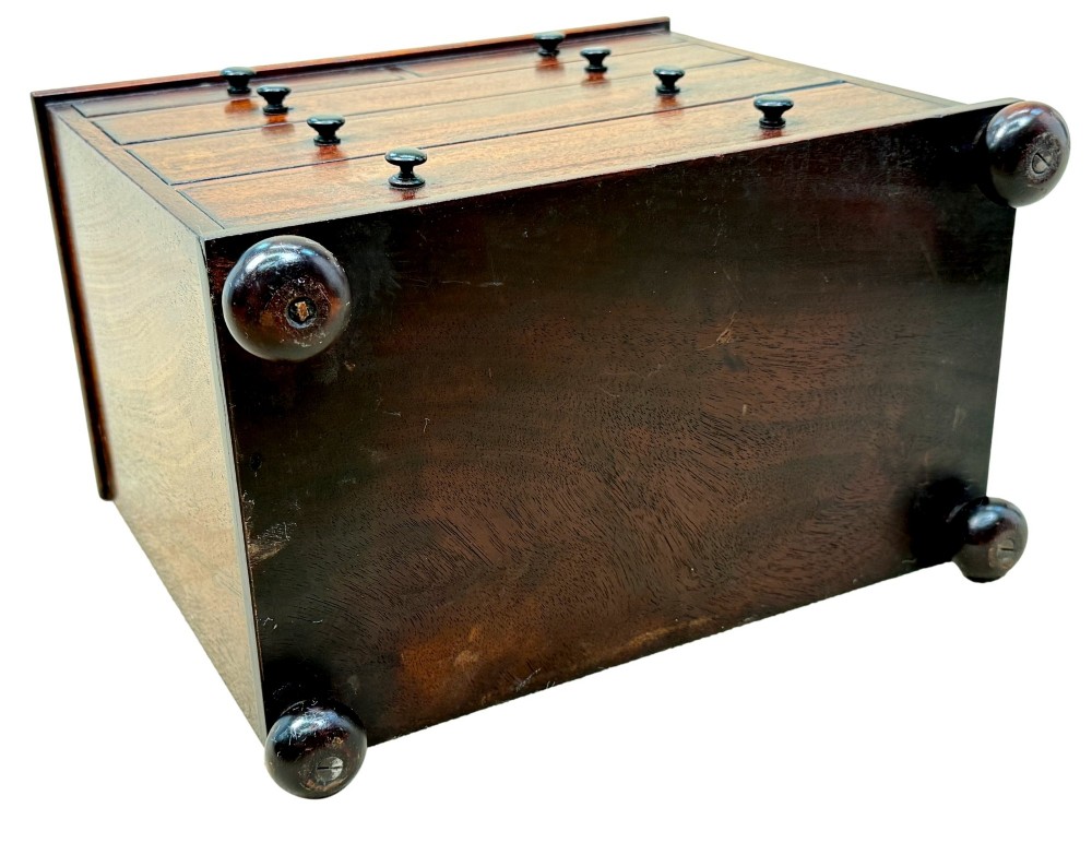 A mid-nineteenth-century miniature mahogany chest of drawers featuring two short over three long drawers, turned dark knobs, and bun feet. View IX