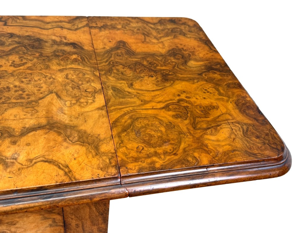 A 19th-century burr walnut Pembroke side table with a single drawer, two drop-down side leaves, turned fluted legs, and brass castors. View V