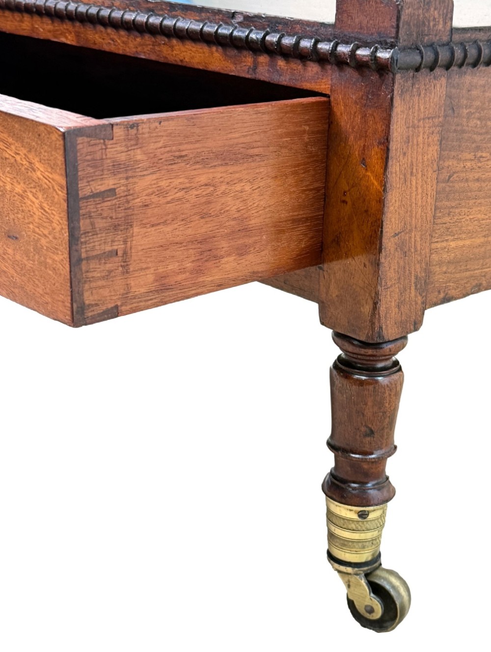 An early nineteenth-century Regency mahogany three-tiered etagere whatnot with turned supports, finials, a lower drawer, and brass castors. View VI