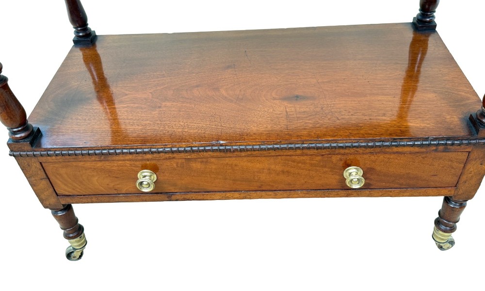An early nineteenth-century Regency mahogany three-tiered etagere whatnot with turned supports, finials, a lower drawer, and brass castors. View VII