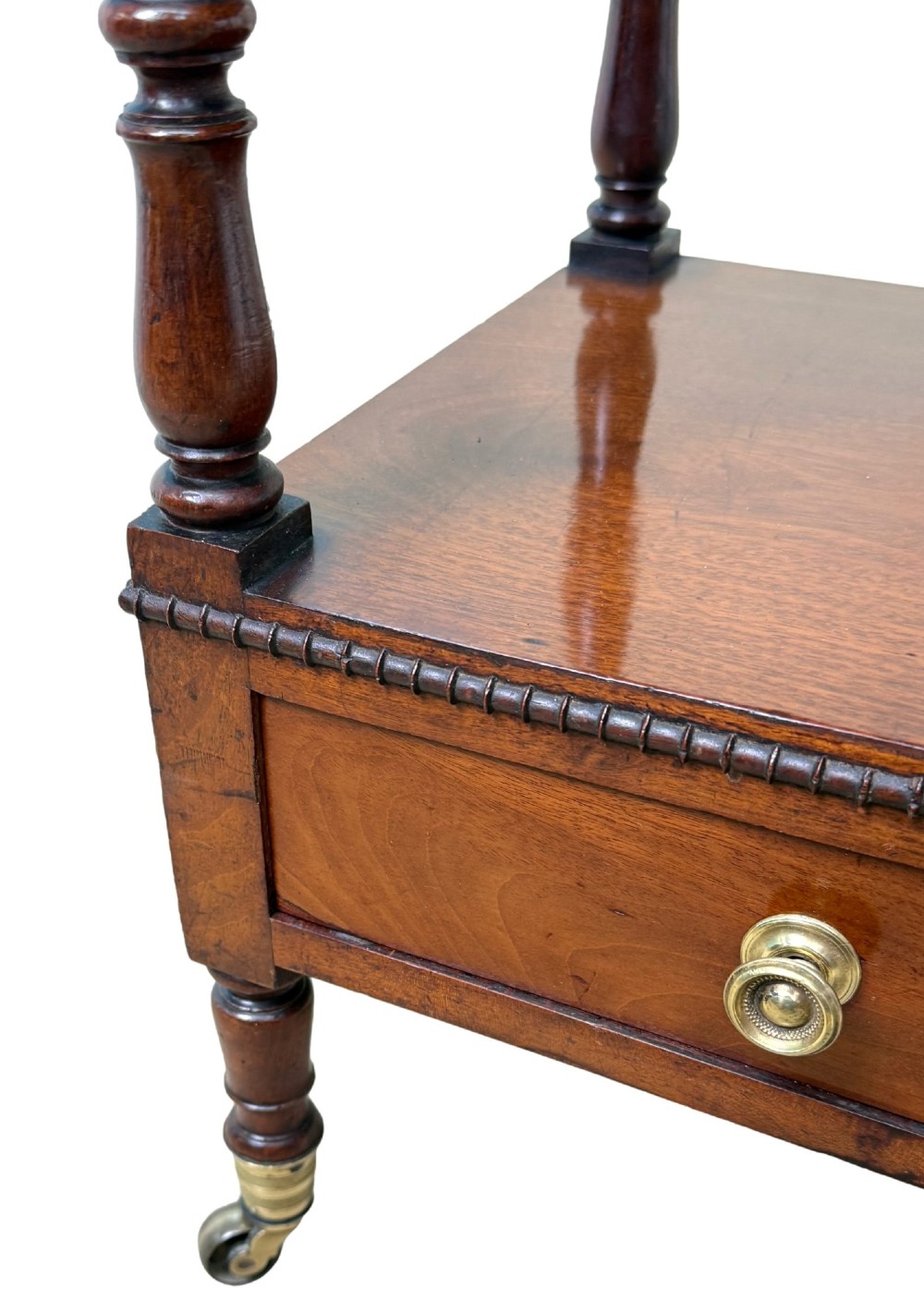 An early nineteenth-century Regency mahogany three-tiered etagere whatnot with turned supports, finials, a lower drawer, and brass castors. View IX