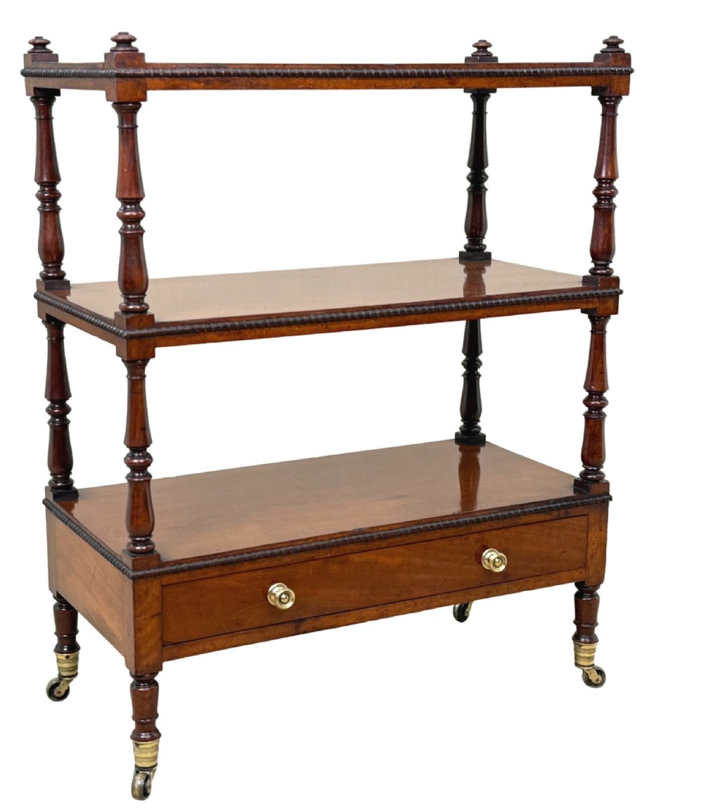An early nineteenth-century Regency mahogany three-tiered etagere whatnot with turned supports, finials, a lower drawer, and brass castors. View X