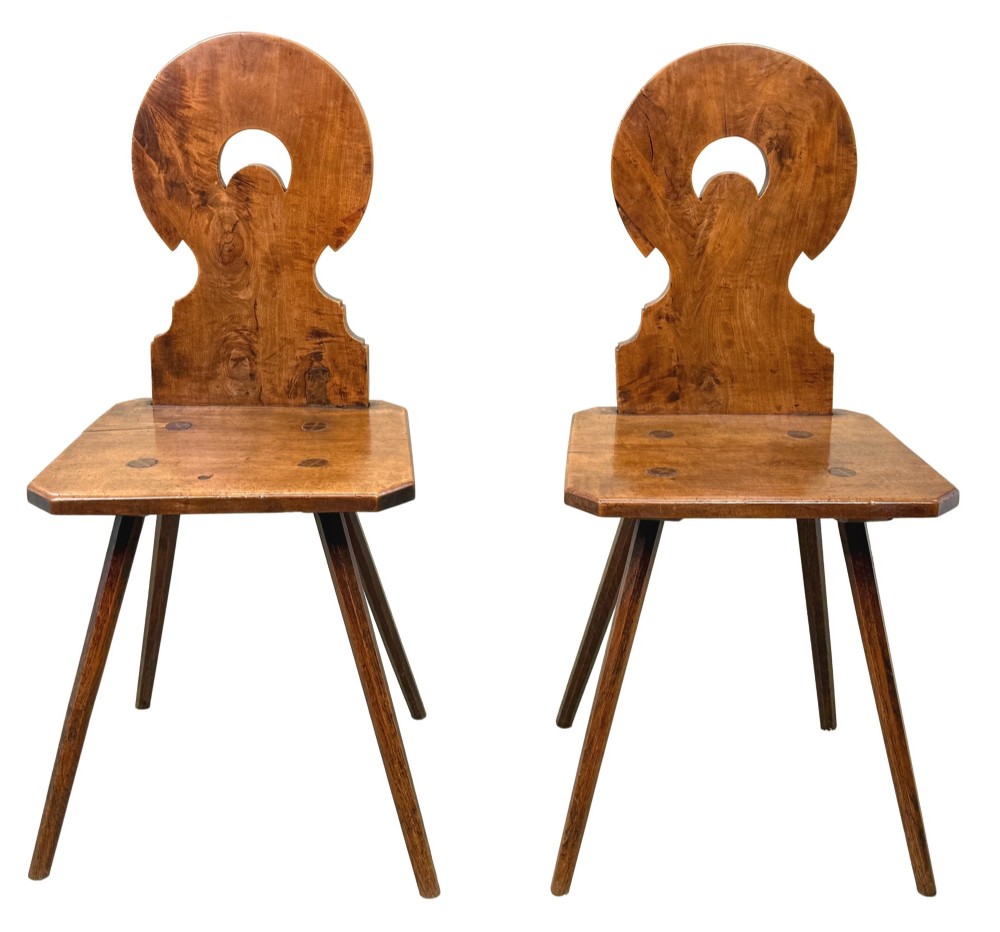 A pair of mid-19th-century Swiss escabelle chairs crafted from warm brown fruitwood, featuring circular carved backrests with cut-out motifs and four splayed tapered legs. View VIII
