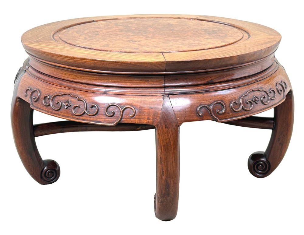 A circular 19th-century Chinese export hardwood coffee table featuring an inset burr wood top, carved scroll aprons, and curved legs.