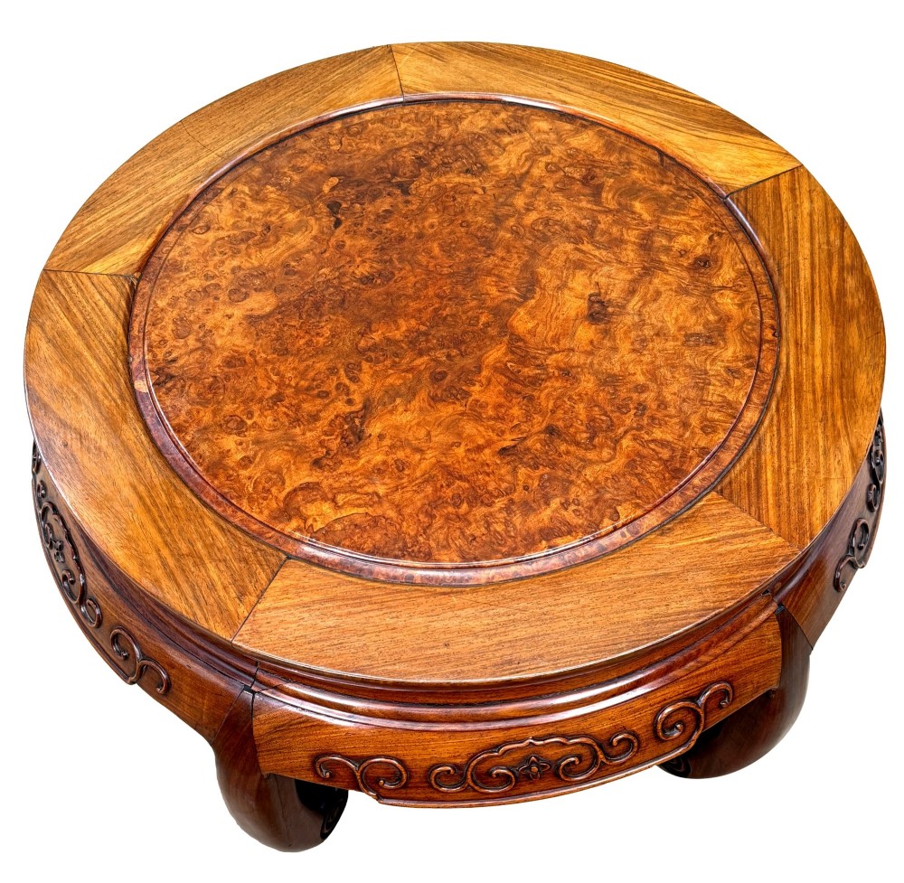 A circular 19th-century Chinese export hardwood coffee table featuring an inset burr wood top, carved scroll aprons, and curved legs. View VI