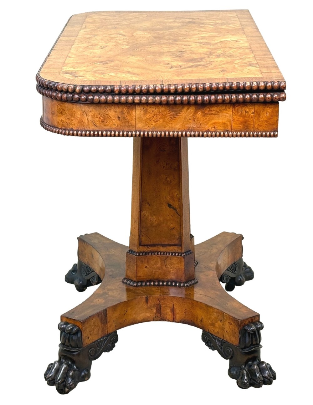 An early 19th-century Regency period pollard oak fold-over tea table featuring a rectangular top, beaded edging, a central pedestal support, and a quadripartite base resting on carved claw feet. View II