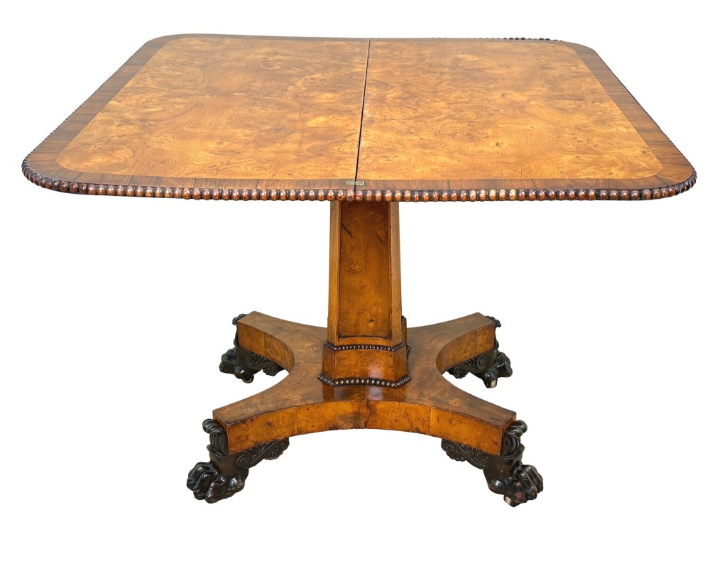 An early 19th-century Regency period pollard oak fold-over tea table featuring a rectangular top, beaded edging, a central pedestal support, and a quadripartite base resting on carved claw feet. View IV