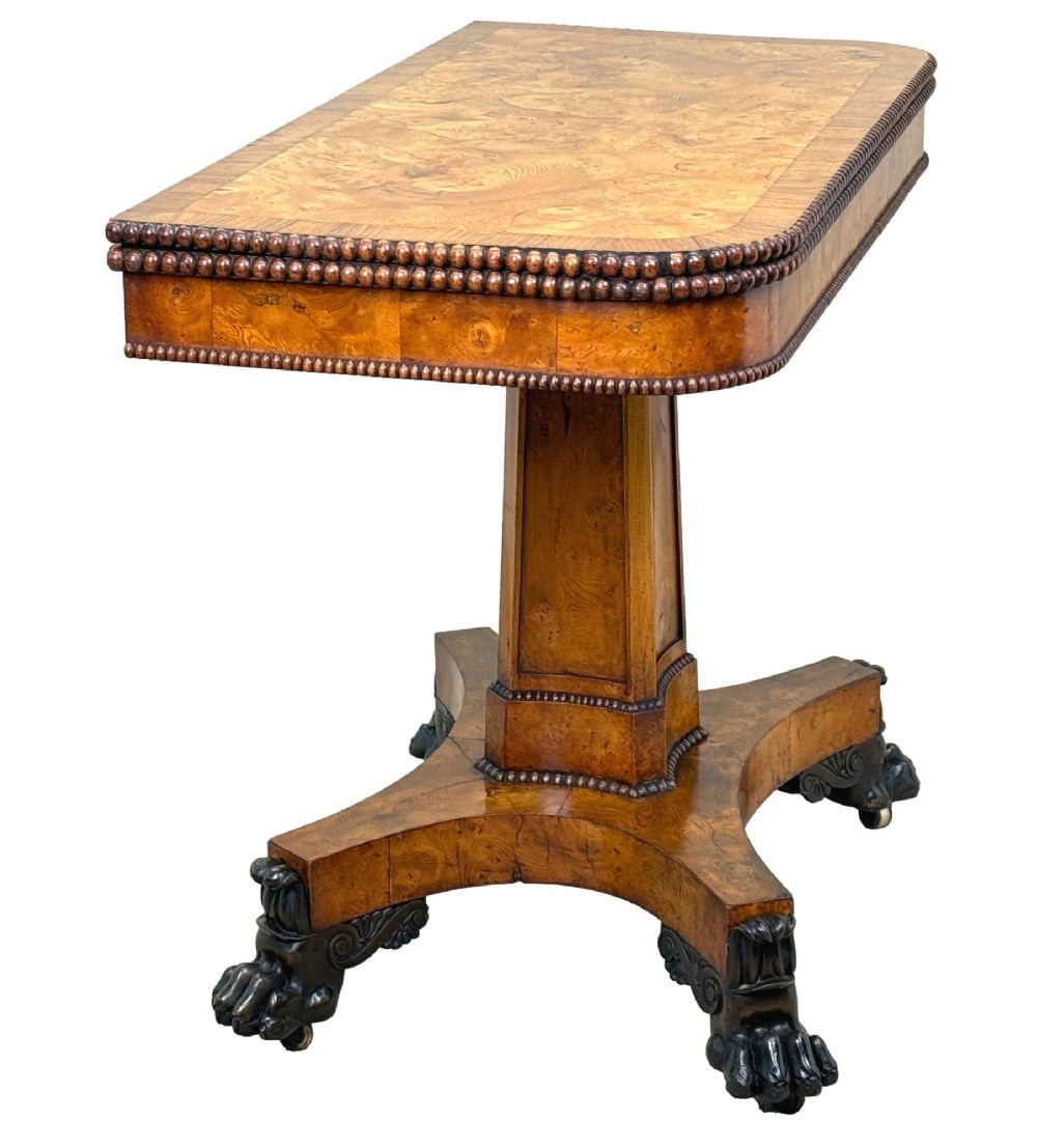 An early 19th-century Regency period pollard oak fold-over tea table featuring a rectangular top, beaded edging, a central pedestal support, and a quadripartite base resting on carved claw feet. View VI