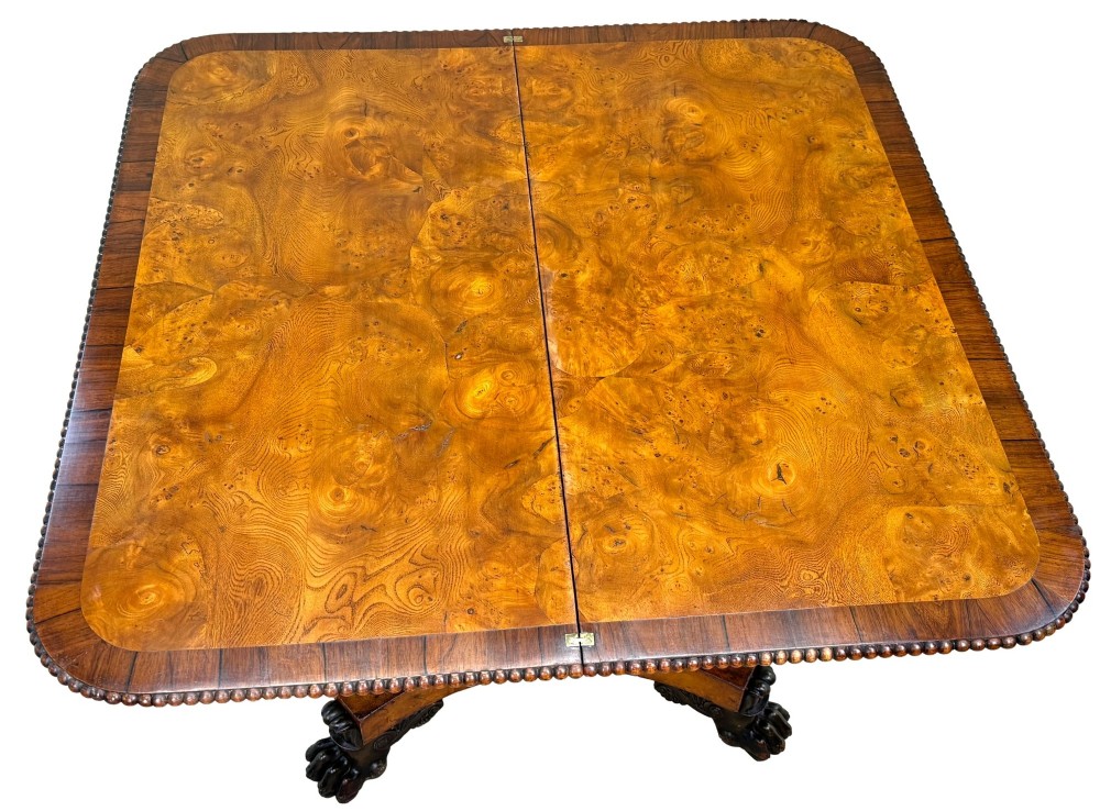 An early 19th-century Regency period pollard oak fold-over tea table featuring a rectangular top, beaded edging, a central pedestal support, and a quadripartite base resting on carved claw feet. View VII