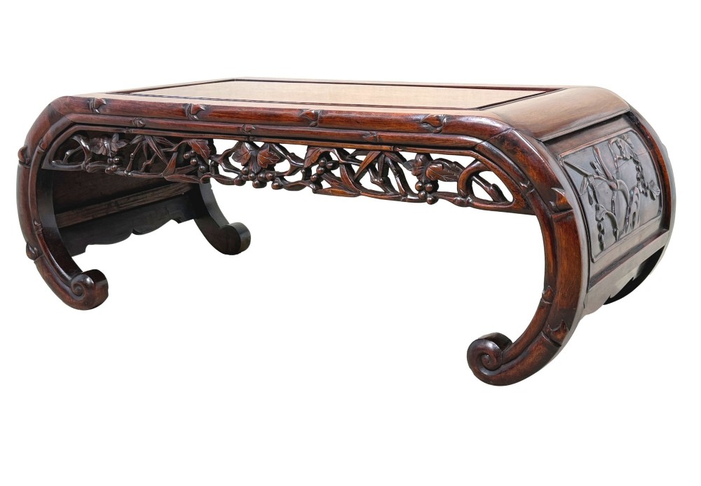 A 19th-century dark hardwood Chinese export opium coffee table featuring scrolled legs and intricately carved pierced floral aprons.