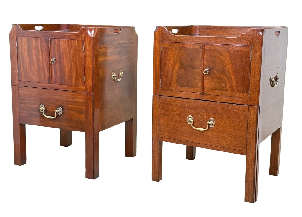 A matched pair of Georgian mahogany bedside tables featuring top tray galleries with cutout handles, double cupboard doors, lower drawers, and brass hardware.