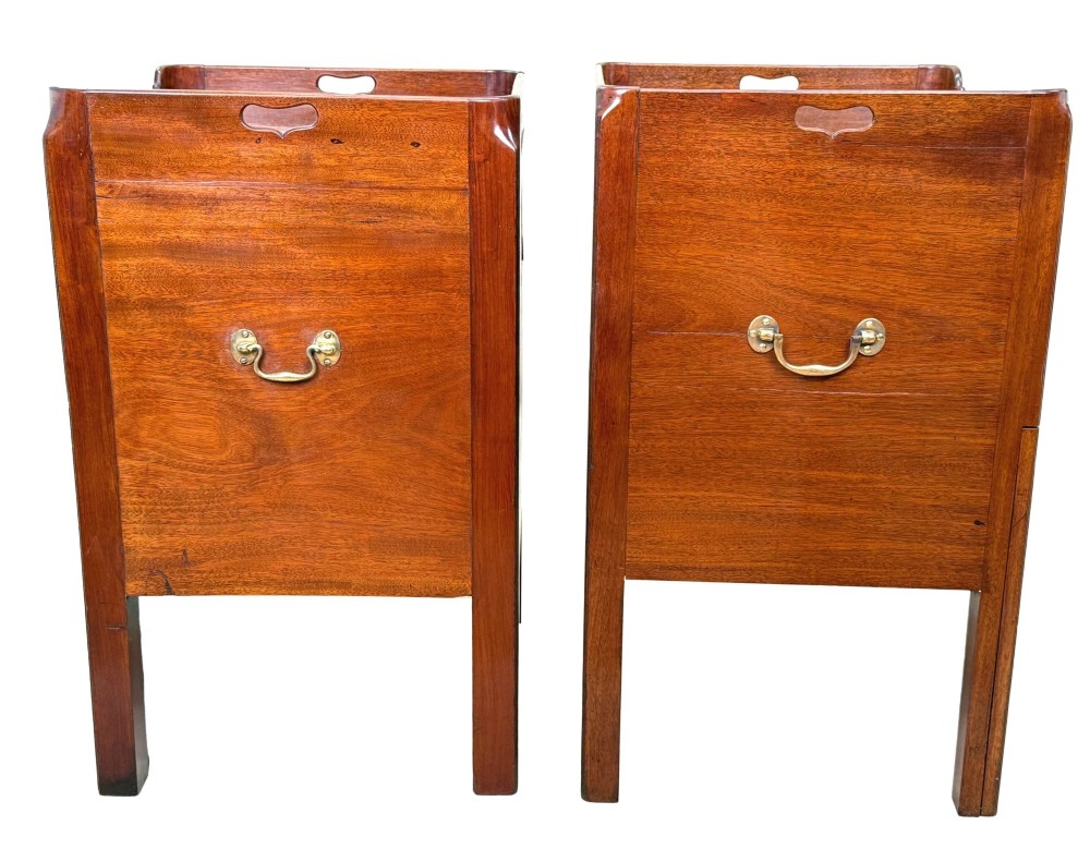 A matched pair of Georgian mahogany bedside tables featuring top tray galleries with cutout handles, double cupboard doors, lower drawers, and brass hardware. View II