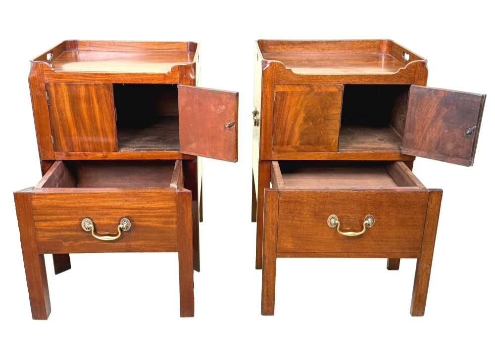 A matched pair of Georgian mahogany bedside tables featuring top tray galleries with cutout handles, double cupboard doors, lower drawers, and brass hardware. View V