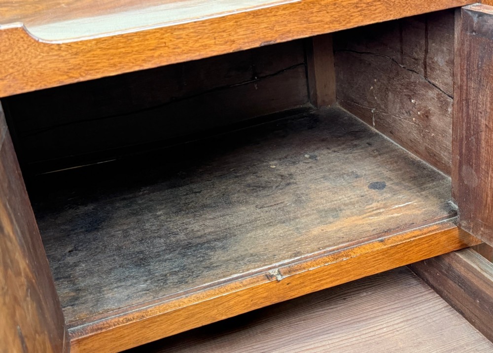 A matched pair of Georgian mahogany bedside tables featuring top tray galleries with cutout handles, double cupboard doors, lower drawers, and brass hardware. View VI