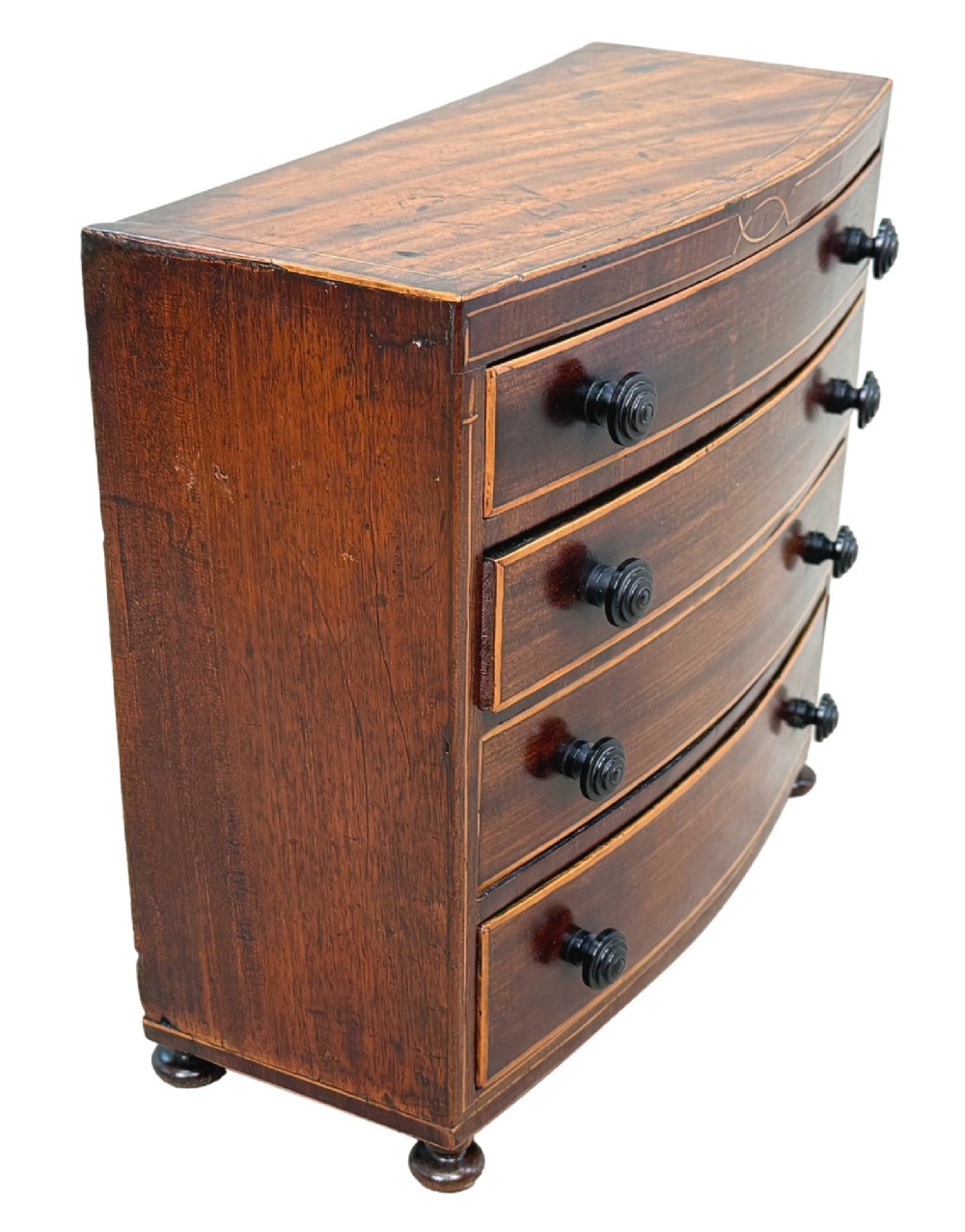 An 18th-century Georgian mahogany miniature bowfront chest of drawers featuring boxwood inlay, four graduated drawers with turned wooden knobs, and low bun feet. View II