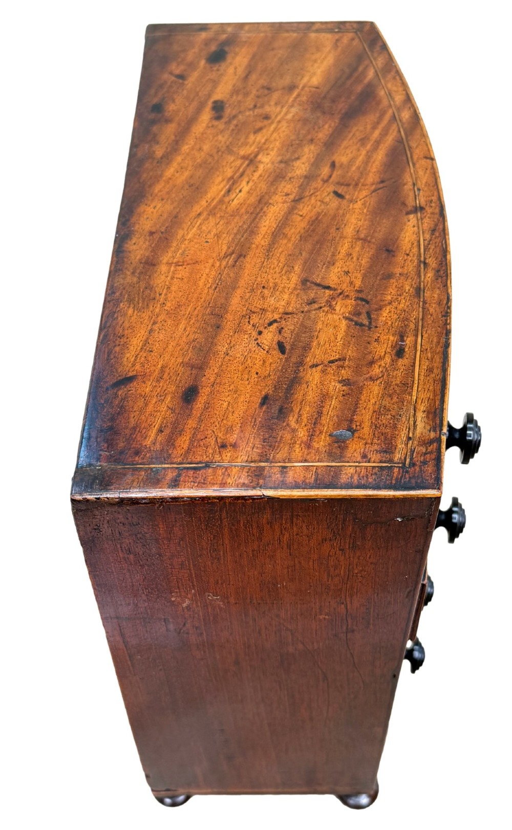 An 18th-century Georgian mahogany miniature bowfront chest of drawers featuring boxwood inlay, four graduated drawers with turned wooden knobs, and low bun feet. View III