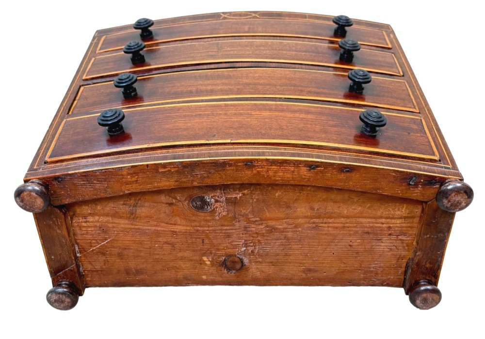 An 18th-century Georgian mahogany miniature bowfront chest of drawers featuring boxwood inlay, four graduated drawers with turned wooden knobs, and low bun feet. View X