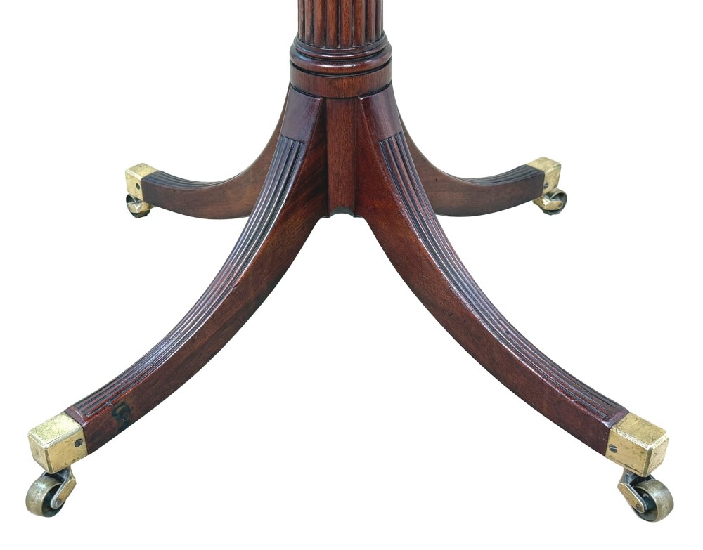 Late eighteenth-century George III mahogany circular lamp table featuring a fluted stem and four reeded legs with brass castors. View IX
