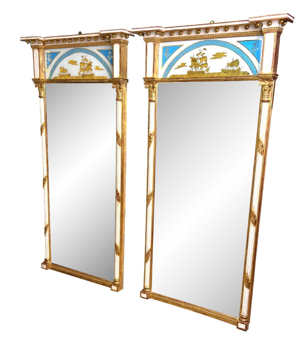 A pair of tall early 19th-century Regency pier mirrors featuring gilded pilasters, breakfront cornices, and upper painted panels depicting maritime sailing vessels.