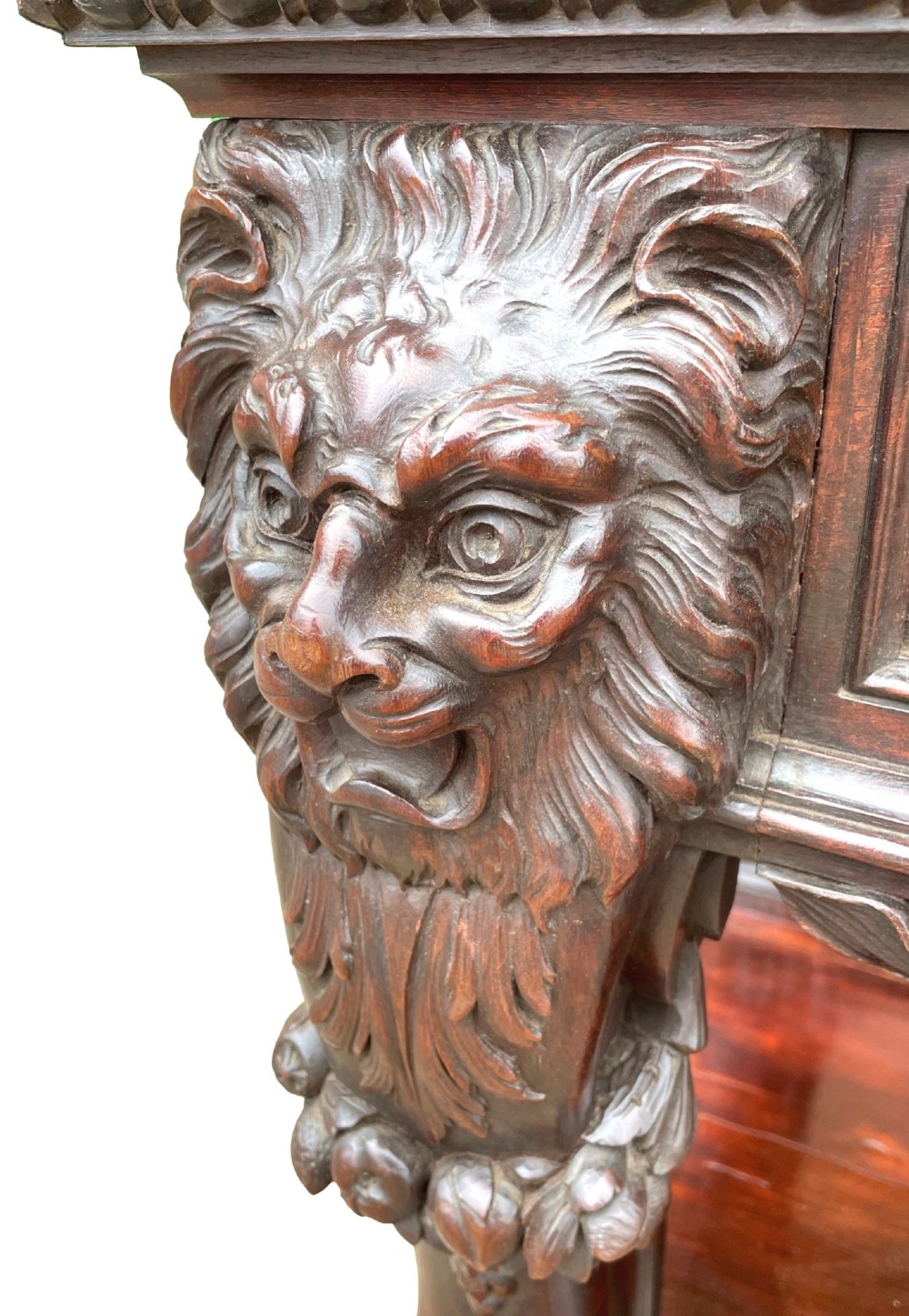 A 19th-century dark mahogany display cabinet featuring a carved crest, glazed doors, and lower support with carved lion mask legs. View IX