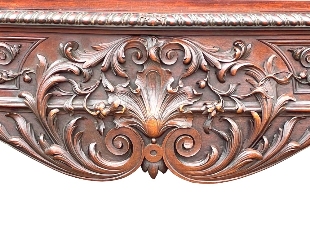 A 19th-century dark mahogany display cabinet featuring a carved crest, glazed doors, and lower support with carved lion mask legs. View XIV