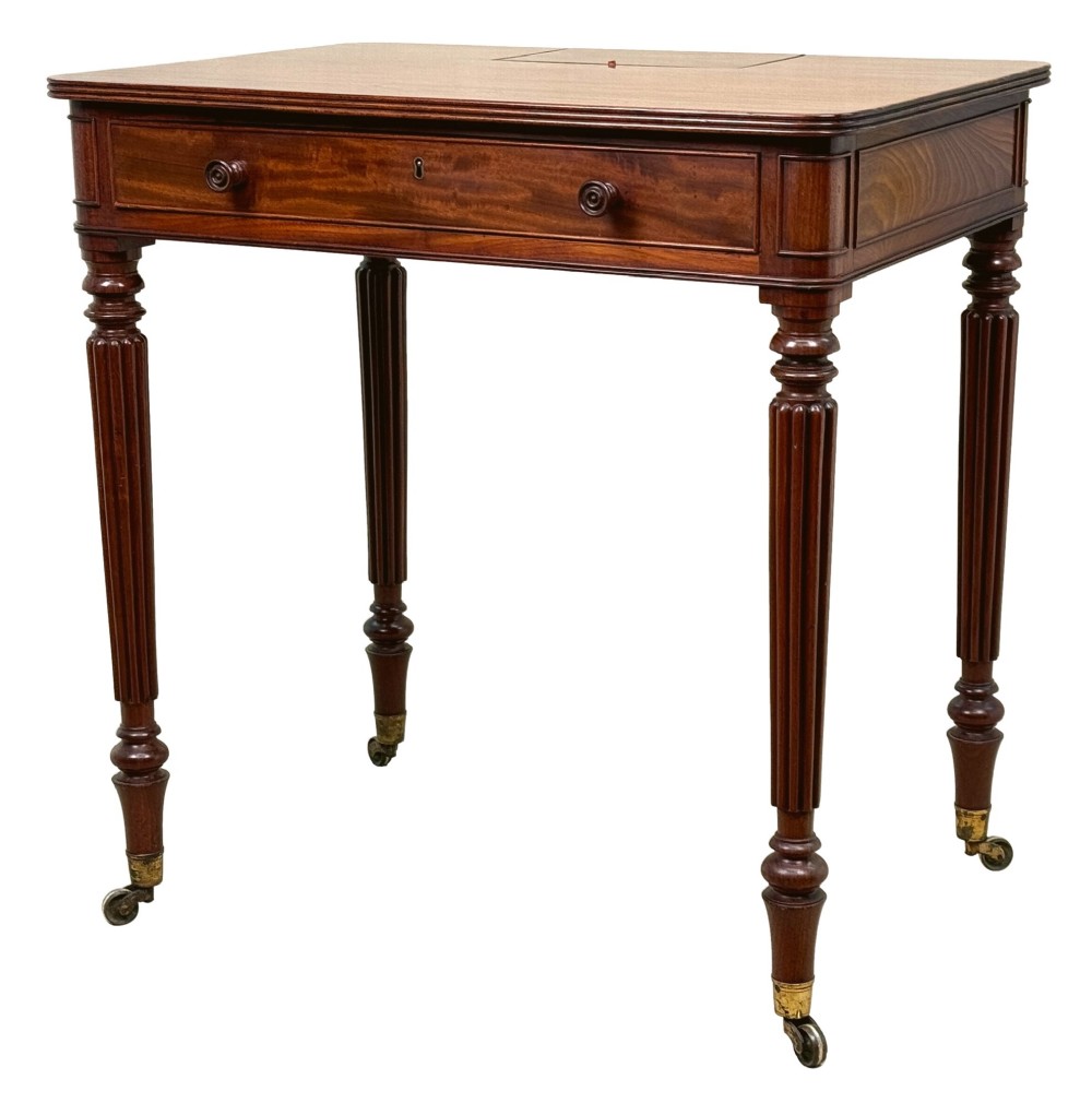A Regency mahogany chamber writing table featuring a single frieze drawer, fluted turned legs on brass castors, and an inset surface hatch.