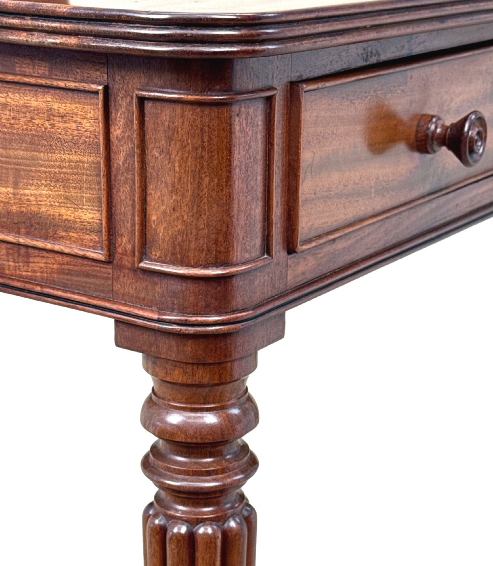 A Regency mahogany chamber writing table featuring a single frieze drawer, fluted turned legs on brass castors, and an inset surface hatch. View VII