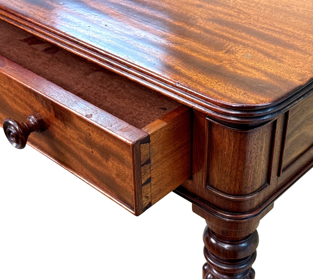 A Regency mahogany chamber writing table featuring a single frieze drawer, fluted turned legs on brass castors, and an inset surface hatch. View VIII