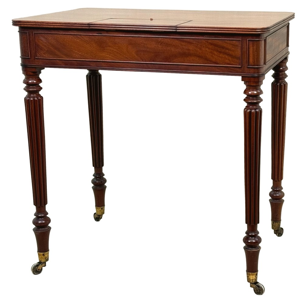A Regency mahogany chamber writing table featuring a single frieze drawer, fluted turned legs on brass castors, and an inset surface hatch. View IX