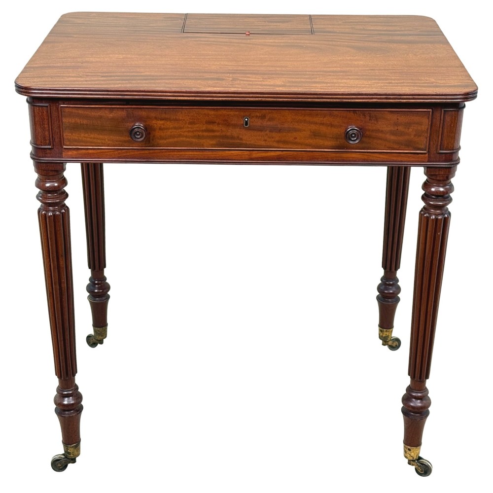 A Regency mahogany chamber writing table featuring a single frieze drawer, fluted turned legs on brass castors, and an inset surface hatch. View X