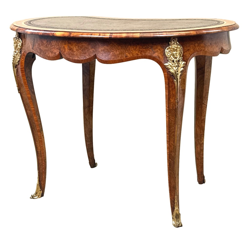 A 19th-century burr walnut kidney-shaped writing table featuring an inset leather top, gilt bronze espagnolette mounts, and cabriole legs. View XIV