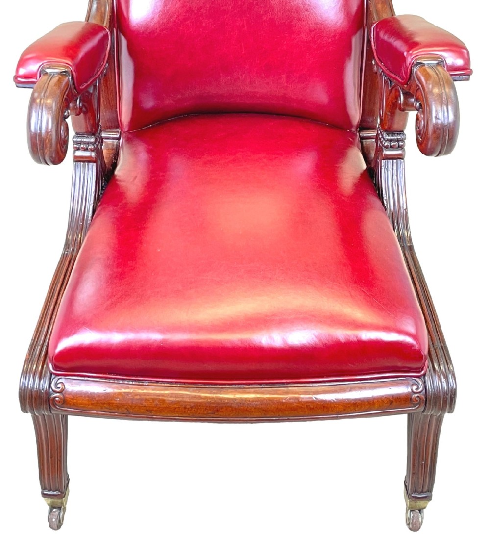 A 19th-century high-back mahogany library chair upholstered in deep red leather with carved scroll armrests and brass castors. View VIII