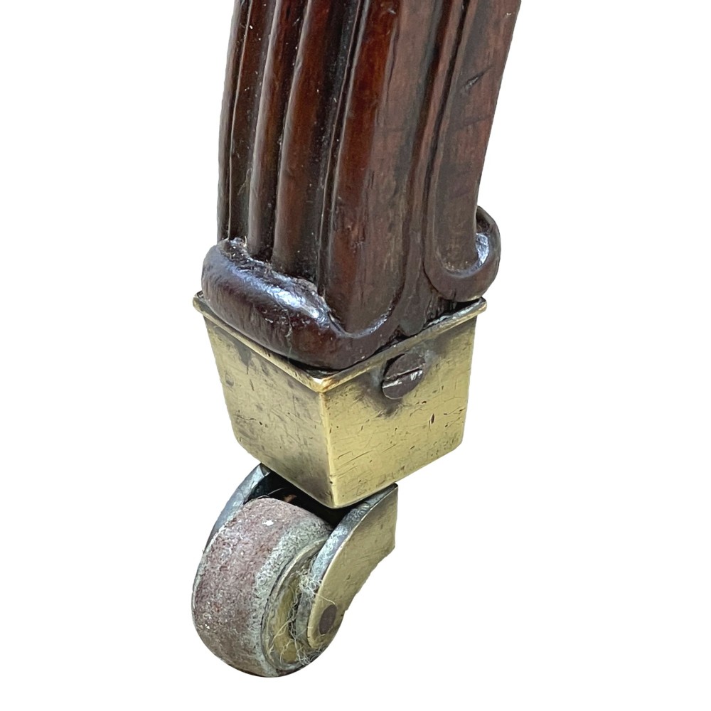 A 19th-century high-back mahogany library chair upholstered in deep red leather with carved scroll armrests and brass castors. View XI
