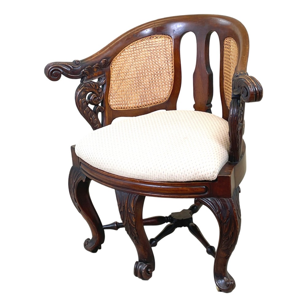 A 19th-century mahogany Burgermeister desk chair featuring a curved backrest with woven cane panels, carved armrests, an upholstered cream seat, and cabriole legs.