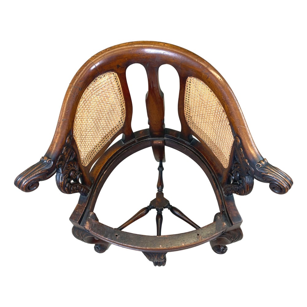 A 19th-century mahogany Burgermeister desk chair featuring a curved backrest with woven cane panels, carved armrests, an upholstered cream seat, and cabriole legs. View VII