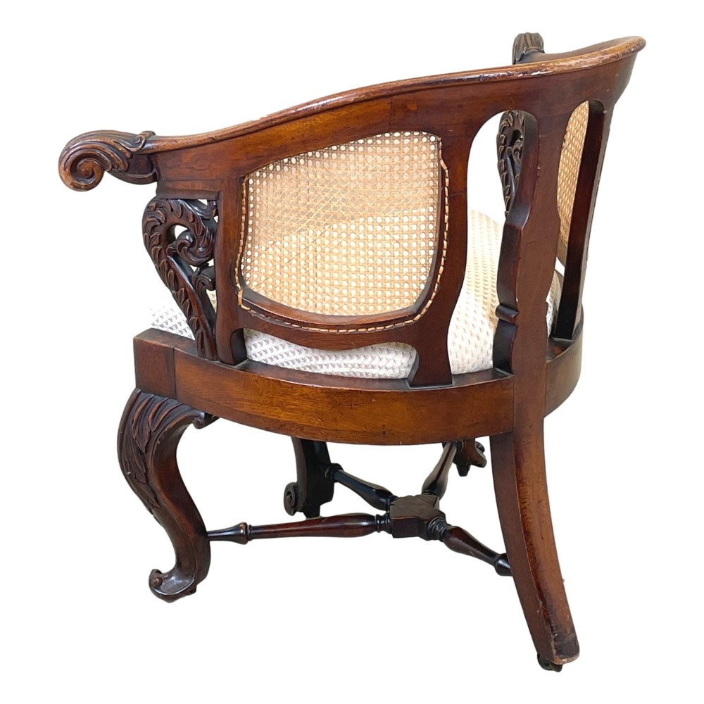 A 19th-century mahogany Burgermeister desk chair featuring a curved backrest with woven cane panels, carved armrests, an upholstered cream seat, and cabriole legs. View VIII