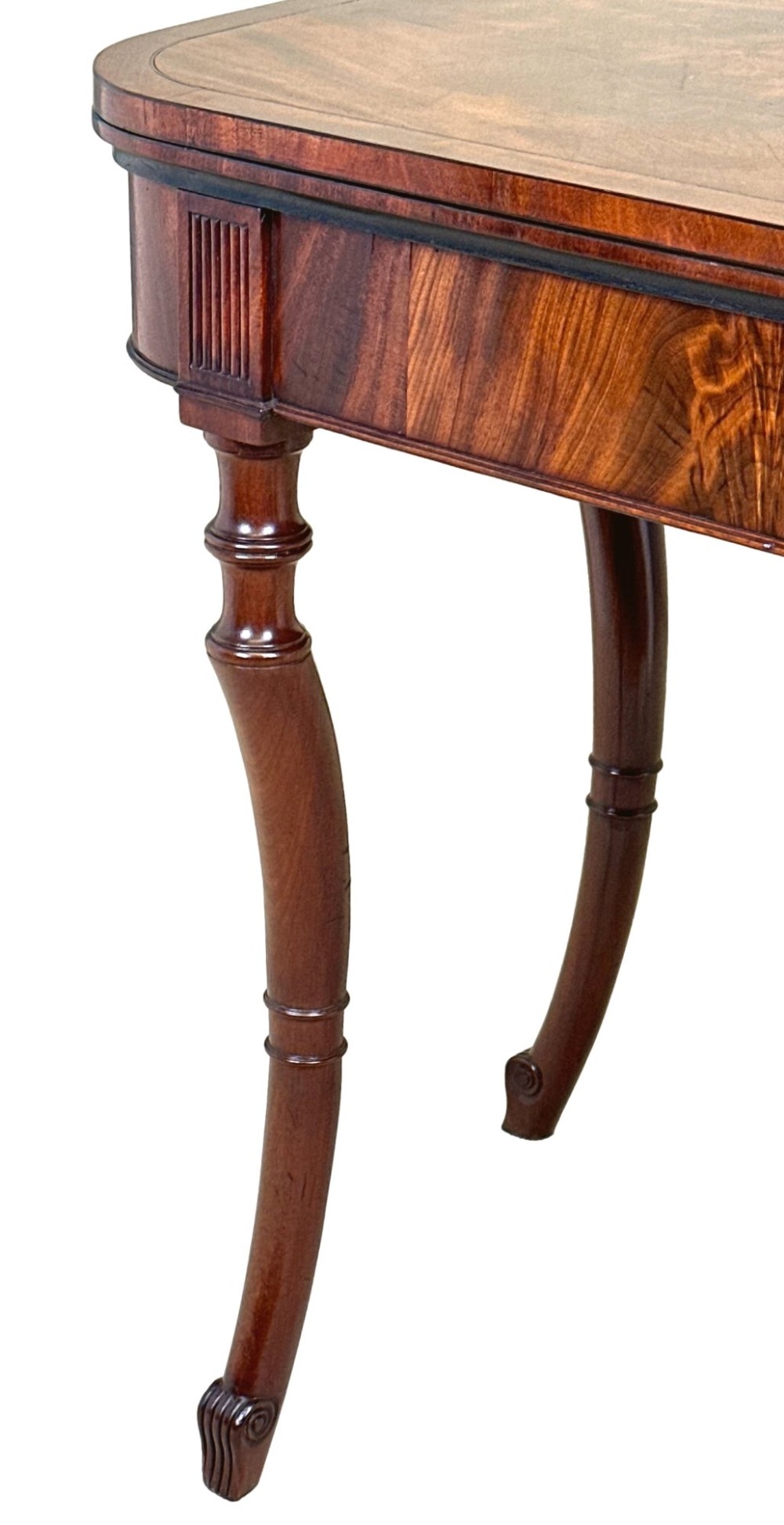 A Regency mahogany fold-over tea table featuring a flame mahogany frieze, reeded corner blocks, and four curved legs with ring-turned detailing. View IV