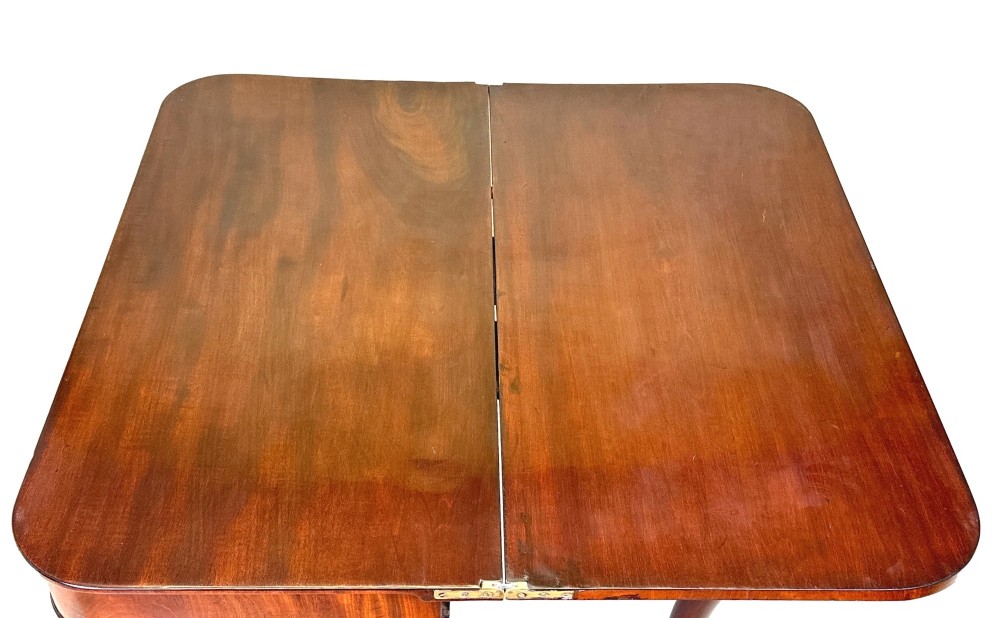 A Regency mahogany fold-over tea table featuring a flame mahogany frieze, reeded corner blocks, and four curved legs with ring-turned detailing. View V