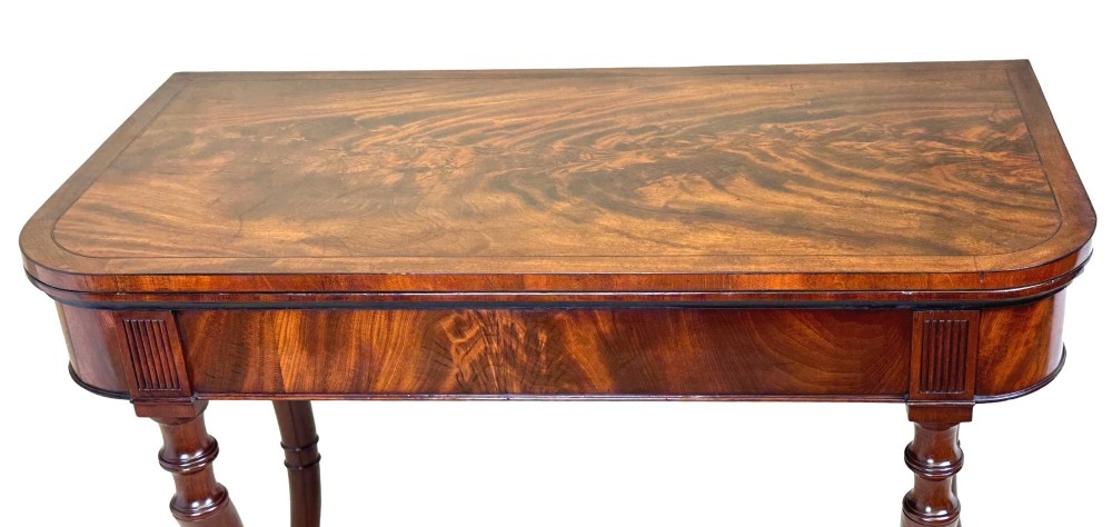 A Regency mahogany fold-over tea table featuring a flame mahogany frieze, reeded corner blocks, and four curved legs with ring-turned detailing. View VI