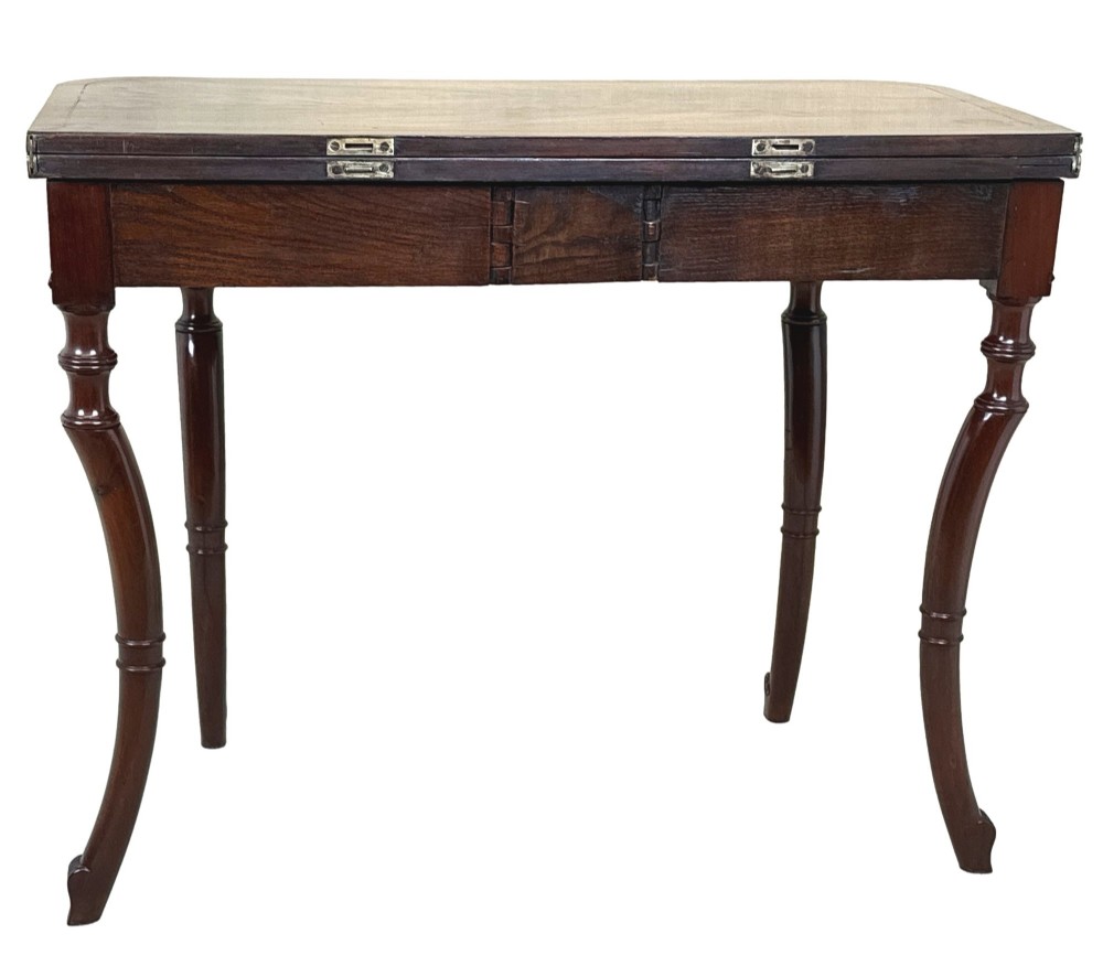 A Regency mahogany fold-over tea table featuring a flame mahogany frieze, reeded corner blocks, and four curved legs with ring-turned detailing. View XII