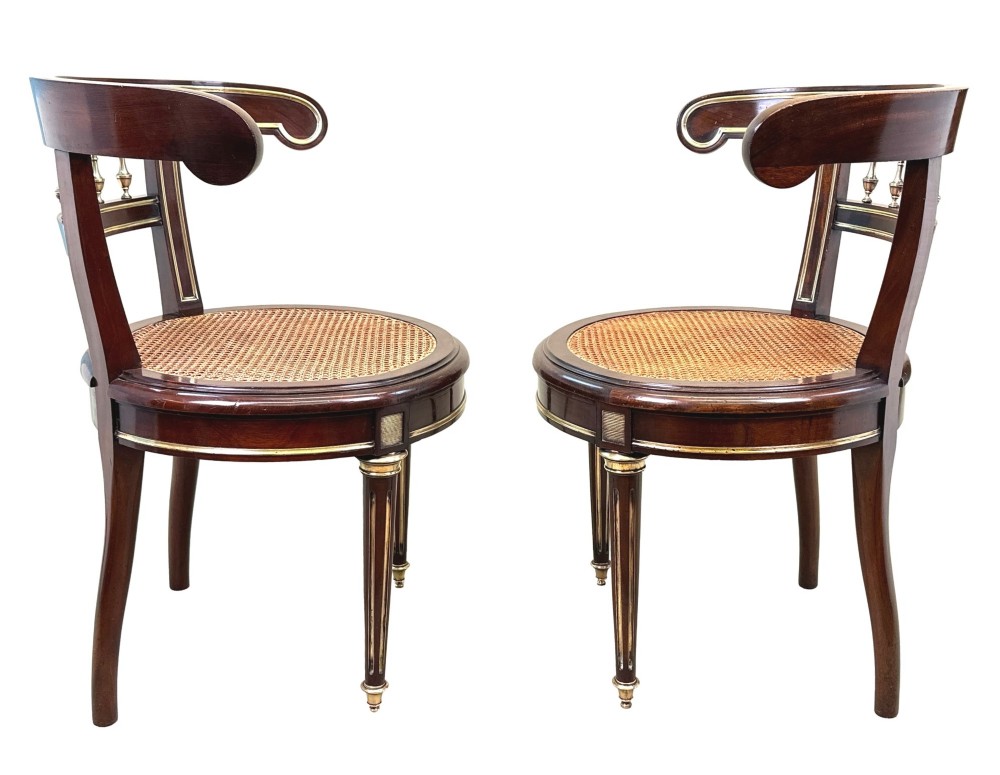 A pair of 19th-century French mahogany curved-back salon chairs with brass mounts, spindle details, woven cane seats, and turned front legs. View II