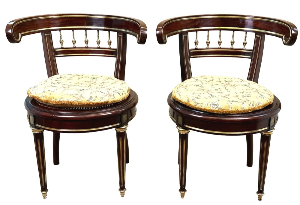A pair of 19th-century French mahogany curved-back salon chairs with brass mounts, spindle details, woven cane seats, and turned front legs. View X