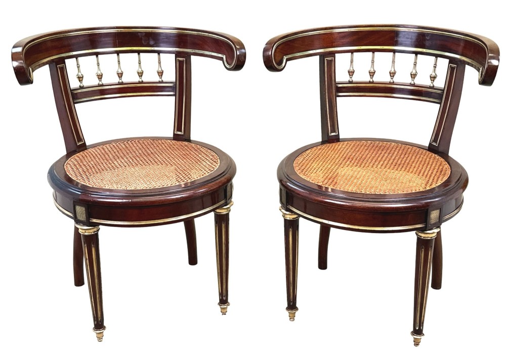 A pair of 19th-century French mahogany curved-back salon chairs with brass mounts, spindle details, woven cane seats, and turned front legs. View XV