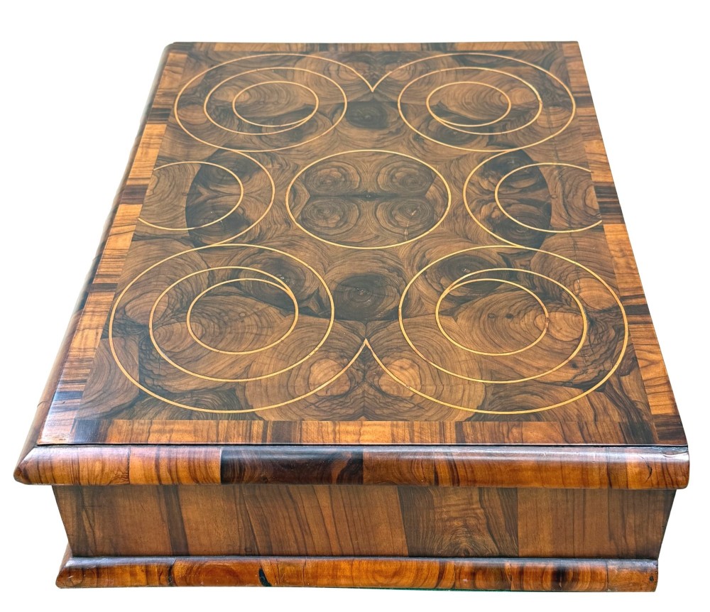 A shallow rectangular William and Mary period wooden box with laburnum oyster veneered patterns, concentric circular stringing on the lid, and a brass keyhole escutcheon on the front panel. View II