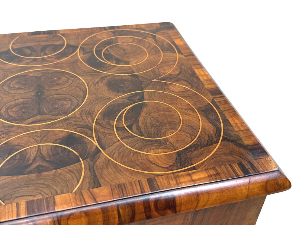 A shallow rectangular William and Mary period wooden box with laburnum oyster veneered patterns, concentric circular stringing on the lid, and a brass keyhole escutcheon on the front panel. View III